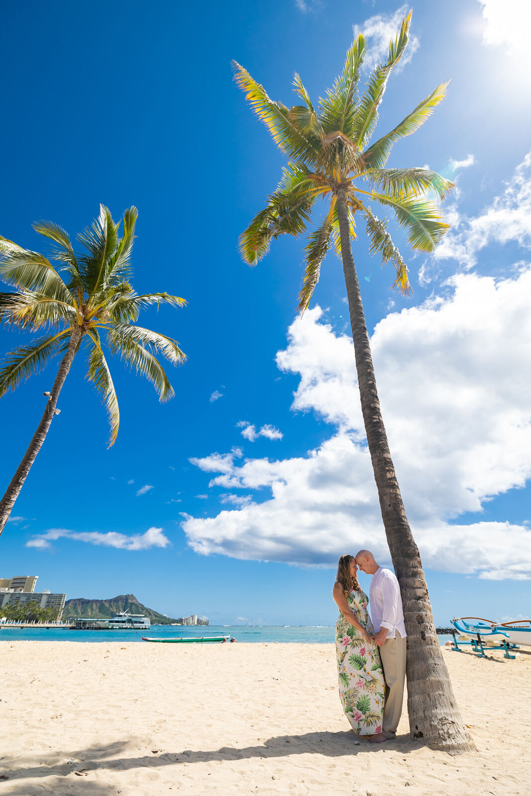 Couple embracing under a palm tree on Waikiki Beach