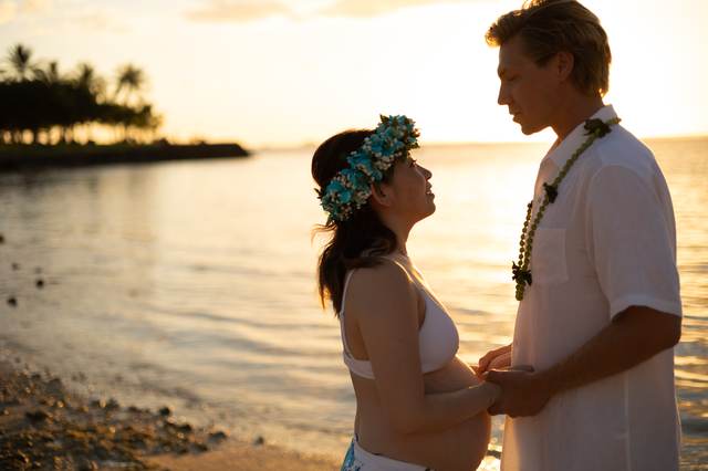 Couple touching foreheads on the beach at sunset wearing a flower crown