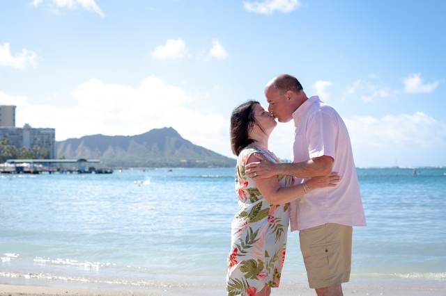 Couple kissing on the beach with Diamond Head visible in the background