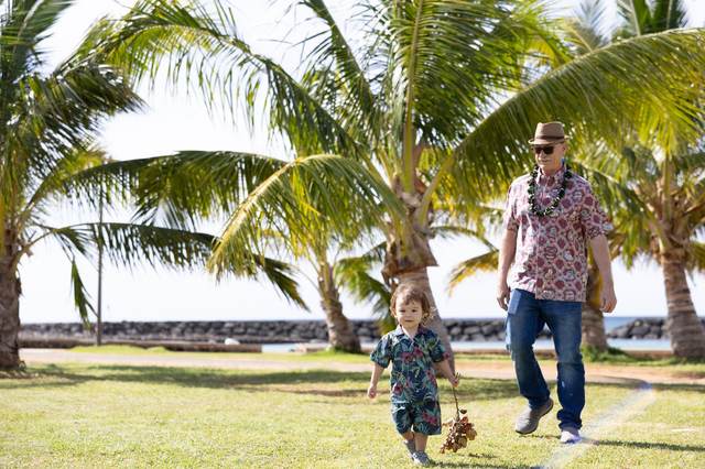Father and son walking together under palm trees