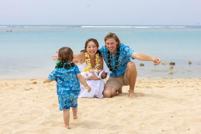 Parents and two young children in matching blue outfits on the beach