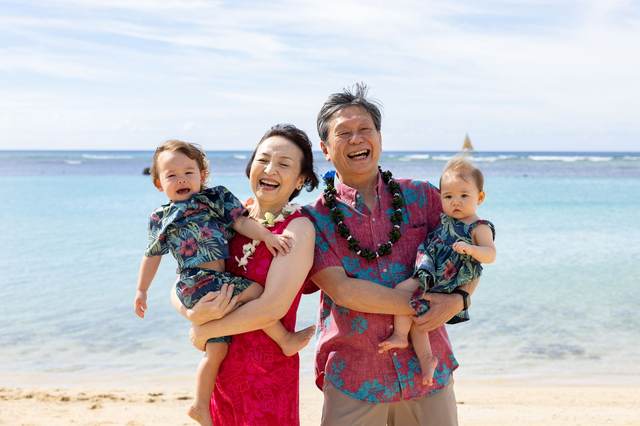 Parents laughing while holding their two children on the beach
