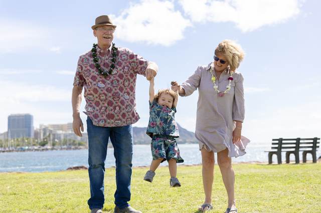 Grandparents dancing with their grandchild in a beachside park