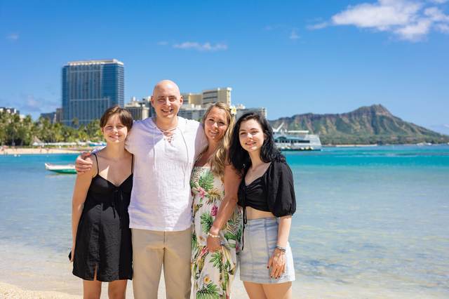 Family of four on Waikiki Beach with Diamond Head and the city skyline