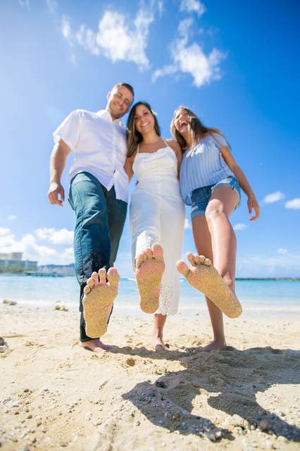 Three family members showing their sandy bare feet on Waikiki Beach