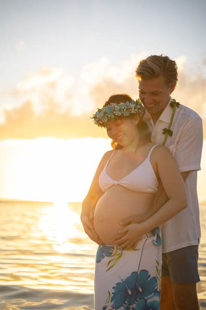 Pregnant woman and partner smiling together at golden hour