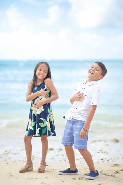 Brother and sister laughing together on the beach