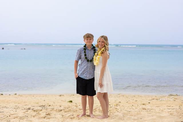 Teenage brother and sister wearing flower leis on the beach