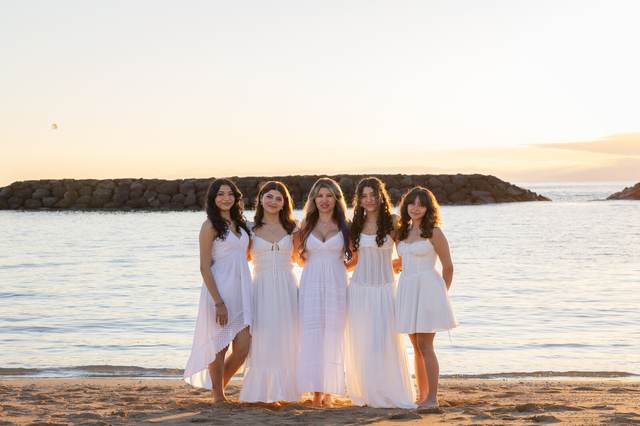 Mother and four daughters standing on the beach at sunset near a rock jetty