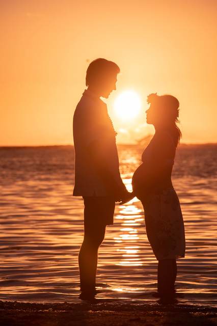 Couple holding hands silhouetted at sunset on the shoreline