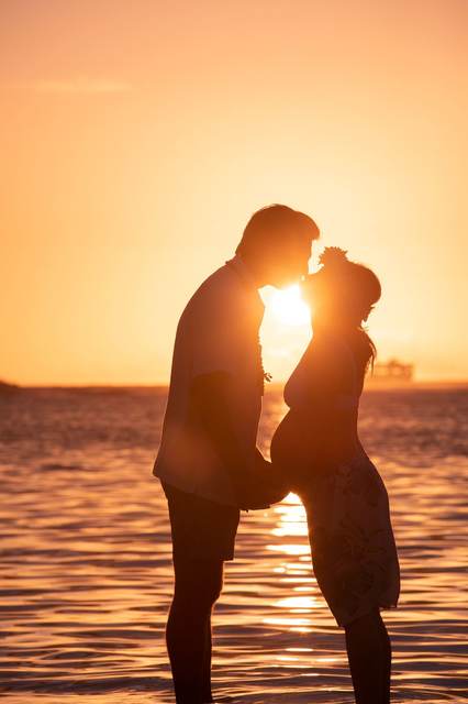 Couple sharing a kiss silhouetted against the sunset over the water