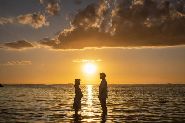 Couple standing together silhouetted against a dramatic sunset sky
